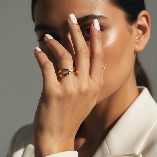 Goudkleurige, gehamerde open ring op de hand van een vrouw met witte nagellak.