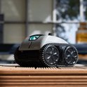 Grijze en zwarte robotstofzuiger met rupsbanden, op een houten ondergrond.