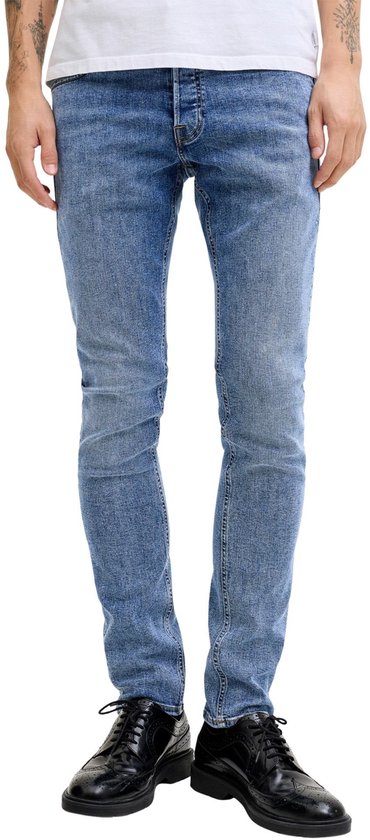 Avant d'un jean slim bleu clair légèrement délavé, porté par un homme avec des chaussures noires.