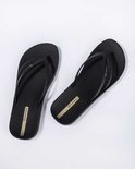 Zwarte Ipanema slippers, schuin van bovenaf gezien, met gevlochten bandjes en gouden logo.