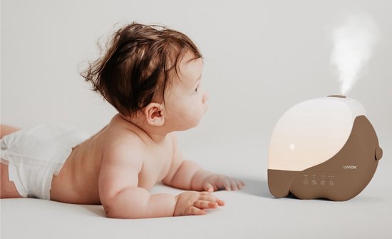 Baby kijkt naar bruine Luvion luchtbevochtiger met witte kap die damp afgeeft, op witte achtergrond.