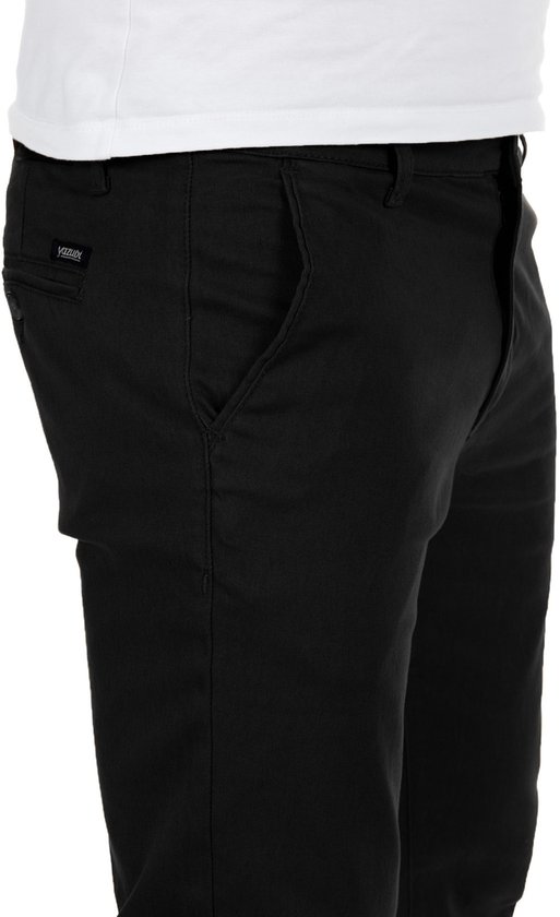 Detailopname van de zijkant van een zwarte slim fit chinobroek, met een open zijzak.