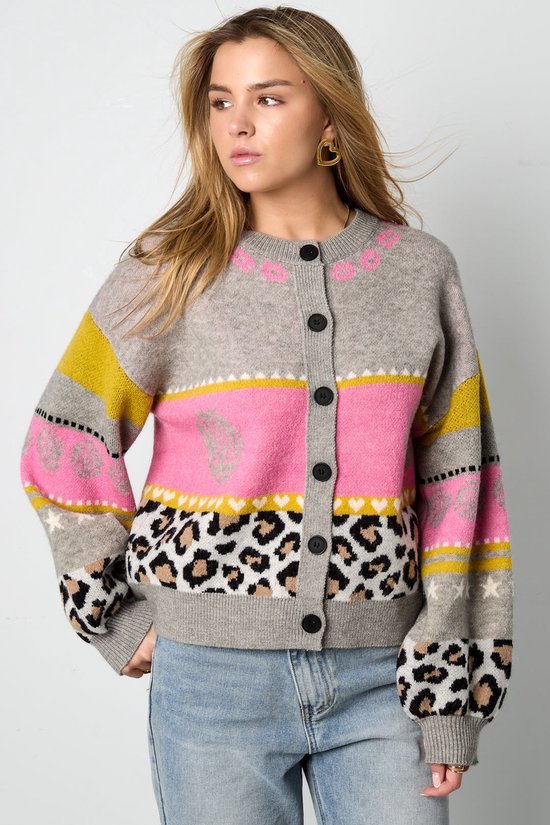 Model draagt grijs vest met roze, gele en zwarte strepen, luipaardprint en bloemenpatronen.