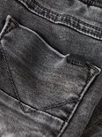 Gedetailleerd zicht op de grijze denim achterzak van de jeans met merklabel.
