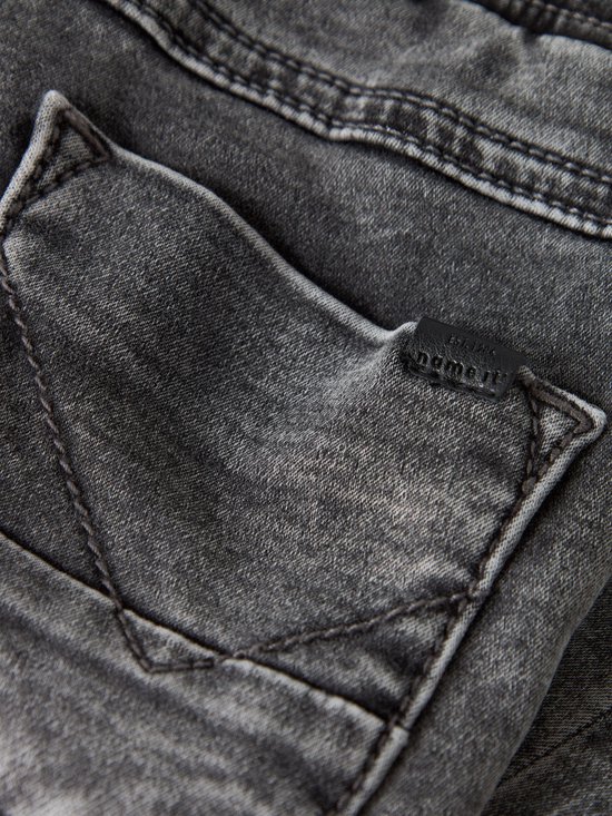 Gedetailleerd zicht op de grijze denim achterzak van de jeans met merklabel.