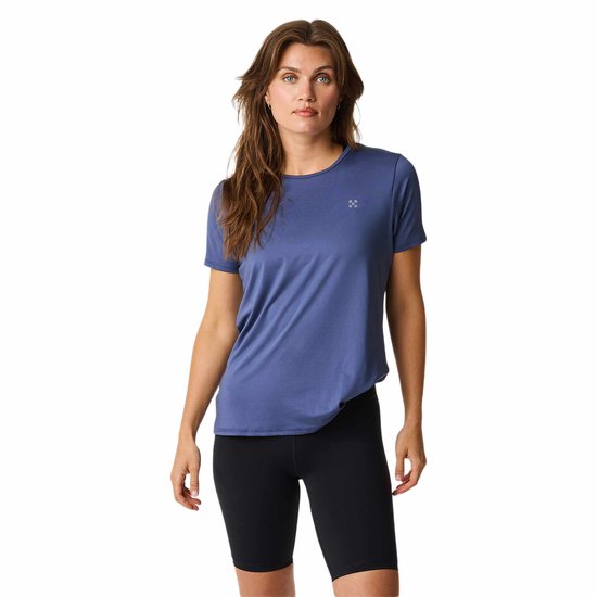Blauw sportshirt met korte mouwen, een ronde hals en een grijs logo op de borst. Gedragen met zwarte fietsbroek.