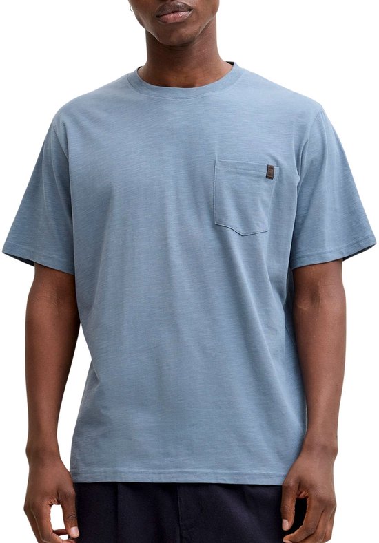 Lichtblauwe T-shirt met borstzakje en bruin label met tekst.