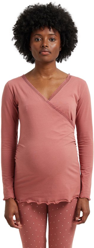 Model in een roze wikkelpyjamatop met kanten afwerking langs de V-hals en een bijpassende pyjamabroek met stippen.