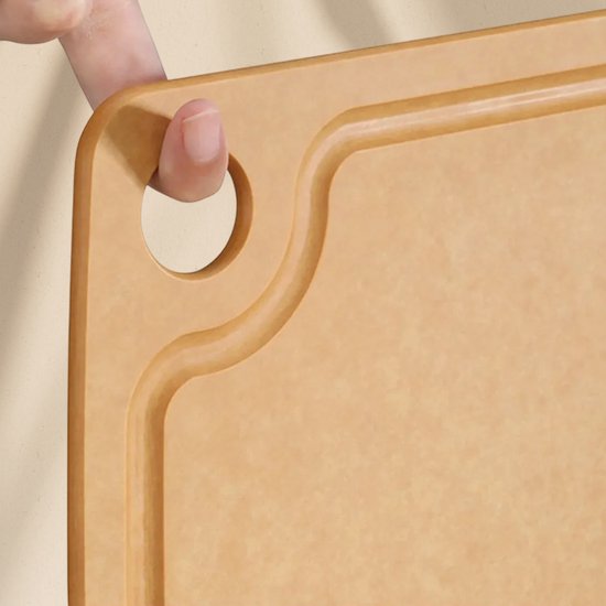 Vinger die de bruine Woodlie snijplank met ophanggat vasthoudt.