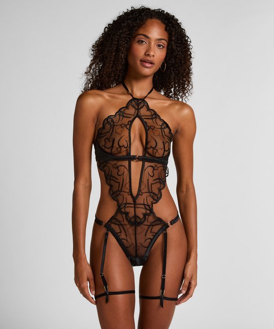 Model in zwarte kanten body met uitsnijdingen, halternek en jarretelaansluitingen.