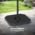 Zwarte parasolvoet met ribbelpatroon, bestaande uit 4 tegels, stevig in een tuin geplaatst.