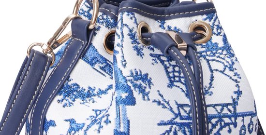 Close-up van sluiting en hengsel van een donkerblauwe emmer tas met wit canvas en blauw Chinoiserie patroon.