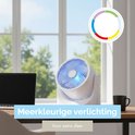 Witte tafelventilator met blauwe verlichting op een bureau. Laptop en mok ernaast. Kleurencirkel bovenaan.