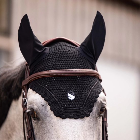 Koppositie van een grijs paard met een zwart, gehaakt oornetje.