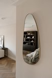 Organische, asymmetrische wandspiegel met gouden rand in een woonkamer