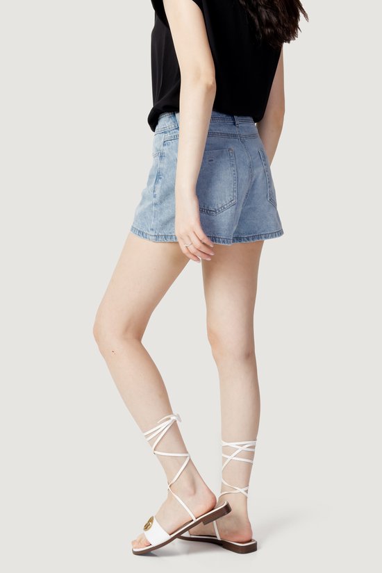 Model met de zijkant naar voren in een lichtblauwe denim skort.