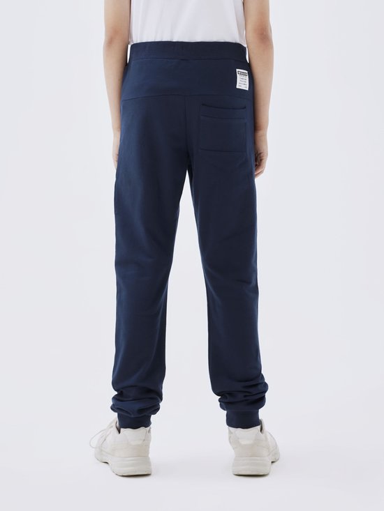Achterkant jongen in donkerblauwe joggingbroek.