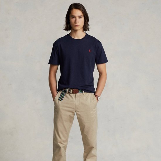 Model in donkerblauw Polo Ralph Lauren T-shirt, beige broek en riem, volledig zicht.