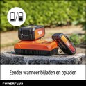 Twee Dual Power accu's op een oranje lader, geplaatst op een boomstronk. Iconen tonen batterijstatus.