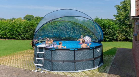 Een rond EXIT zwembad met vier spelende kinderen en een transparante koepel, in een tuin.