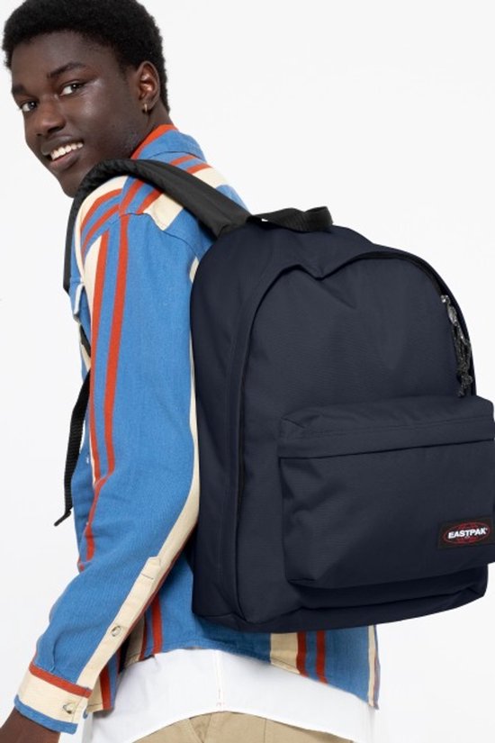 Jonge man draagt een donkerblauwe Eastpak rugzak over zijn schouder.