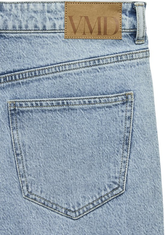 Detail van de achterkant van een lichtblauwe jeans met een bruin lederen label met VMD en een zak.
