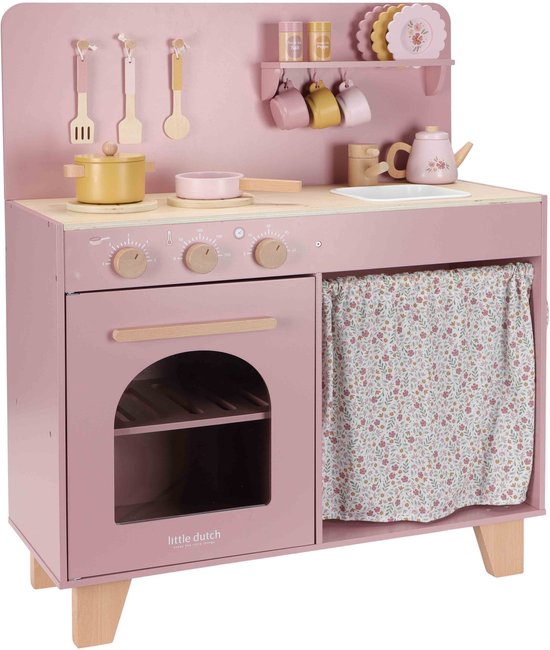 Roze speelgoedkeuken met houten details, bloemenpatroon gordijn, ingebouwde oven en accessoires.