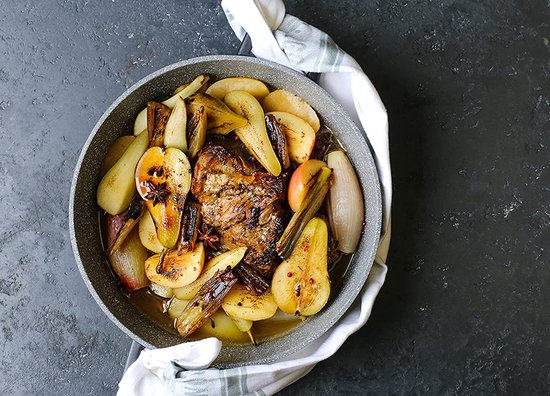 Gevogelte met geroosterde peren, uien en kaneelstokjes in een kookpan. Bestreken met saus.