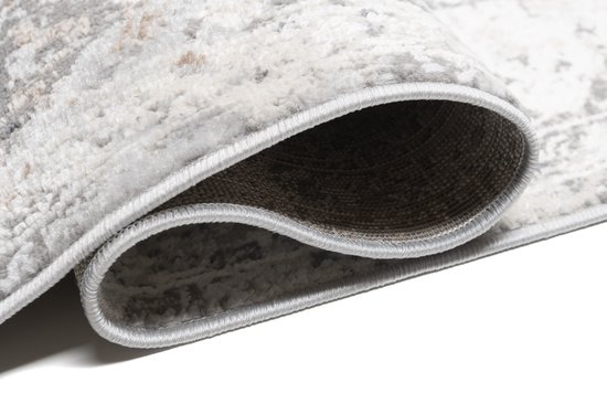 Détail du bord d'un tapis vintage beige clair avec motif détaillé.