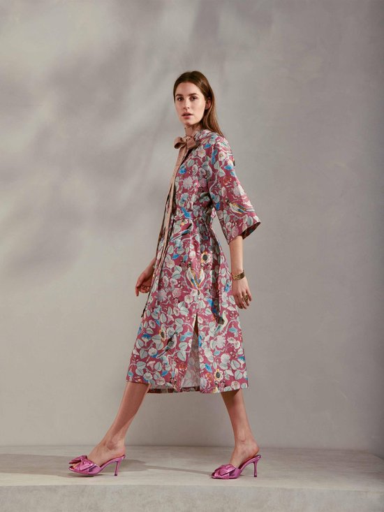 Vrouw in paarse kimono met bloemen- en vogelprint, ceintuur in de taille, strik in de nek.