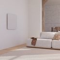 Witte paneelradiator hangend aan een witte muur in een woonkamer.