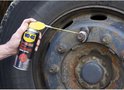 Man spuit WD-40 Specialist Super Kruipolie op de wielmoeren van een vrachtwagen.