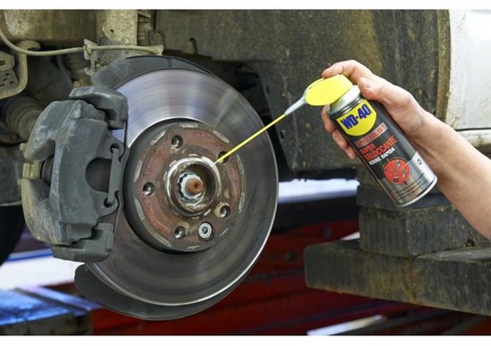 Man spuit WD-40 Specialist Super Kruipolie op een remklauw van een auto.