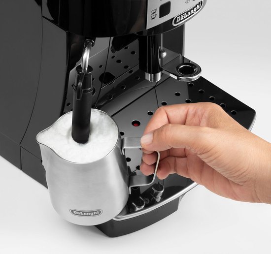Hand stoomt melk in een RVS kannetje met de zwarte De'Longhi Magnifica S.