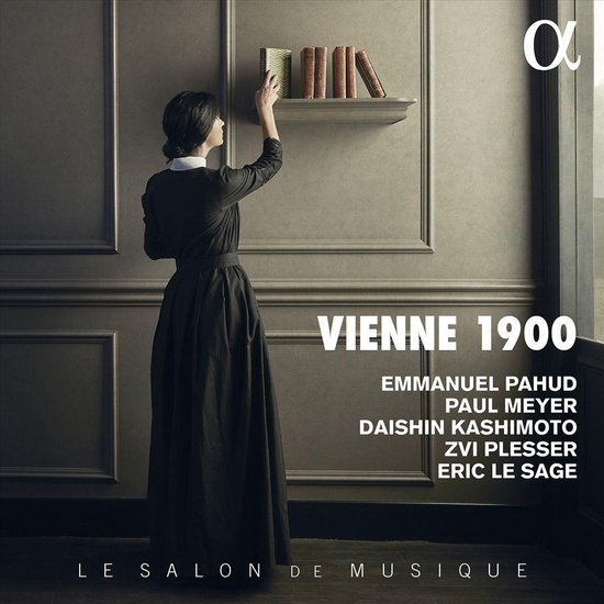 Vrouw in zwart kleed raakt een boek aan op een boekenplank. 'VIENNE 1900' tekst.