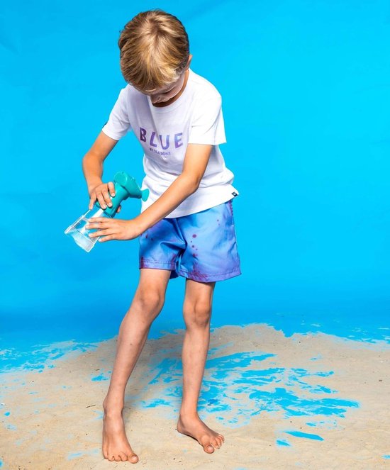 Jongetje met witte T-shirt met tekst 'BLUE BY SEASONS', draagt een lichtblauwe zwembroek met paarse spatten.