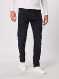 Man in een donkerblauwe jeans en een wit shirt met lange mouwen.