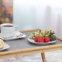 Ontbijt op bed dienblad met een kop koffie, broodje, aardbeien en druiven.