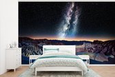 Behang - Fotobehang Melkweg boven een berglandschap bij zonsondergang - Breedte 345 cm x hoogte 220 cm