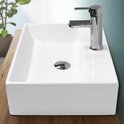 Lavabo carré en céramique blanche avec un robinet chromé et une évacuation, sur un plan de travail en bois.