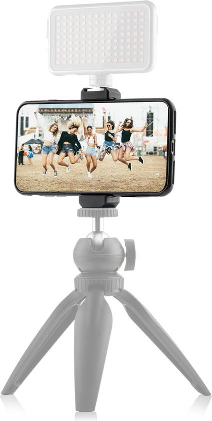 Een smartphone met een foto van vijf springende meisjes op een festival, bovenop een MOJOGEAR LED lamp en een grijs statief.
