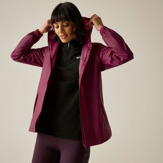 Femme aux cheveux foncés portant un imperméable violet et un pull polaire noir, ajustant sa capuche.