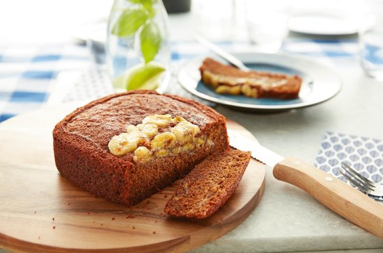 Bananenbrood op een houten plank, gegarneerd met plakjes banaan.