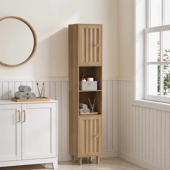 Hoge houten kast met gesloten deuren met verticale groeven en gouden knoppen. Twee open vakken in het midden bevatten handdoeken en stokjes. Eikenlook.