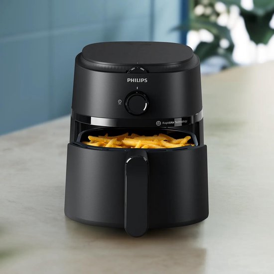 Zwarte Philips Airfryer met een volle mand goudbruine frietjes, met deksel en mand erin.