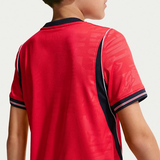 Achterkant van een rood voetbalshirt, detail van de navy zijkanten en witte biezen. Het shirt heeft een subtiel, zichtbaar patroon.
