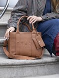 Bruine tote bag met 'CHARM LONDON' in reliëf, draagbanden en bijpassend etui.