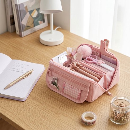 Roze etui met dubbele rits, gevuld met pennen, schaar en andere kantoorspullen. Voorvak met ruitjes en bloemdecoratie.