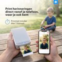 Een man print een foto van een lachende jongen vanaf zijn telefoon met een Silvergear printer in een park.