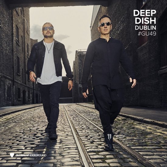 Twee mannen lopen door een straat, met tekst 'DEEP DISH DUBLIN #GU49'.